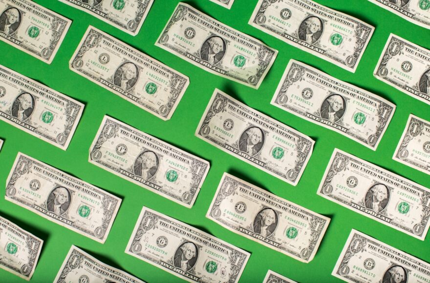 Grid of one-dollar bills arranged in a diagonal pattern on a bright green background, illustrating Colorado child support guidelines.