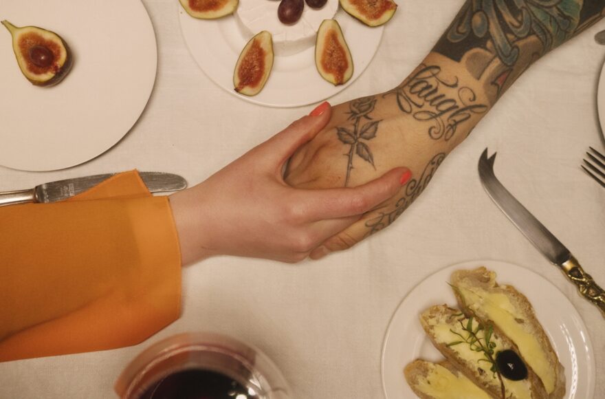 Overhead view of sliced figs on white plates with a tattooed hand resting near a knife and linen napkin, overlaid with text reading "The Prenup Power Hour" from Family Law Fridays.